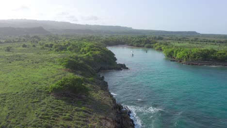 Spektakuläre-Drohne,-Die-An-Einem-Sonnigen-Tag-über-Das-Atemberaubende-Blaue-Wasser-Der-Bucht-Von-Playa-Diamante-Fliegt,-Umgeben-Von-Grünem-Gelände