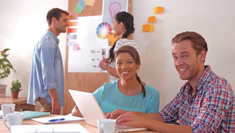 Creative-team-using-laptop-computer-while-their-colleagues-looking-at-color-sample