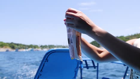 una persona pelando una barra de helado en un barco en phuket, tailandia, bajo la luz del día brillante con vistas panorámicas al océano