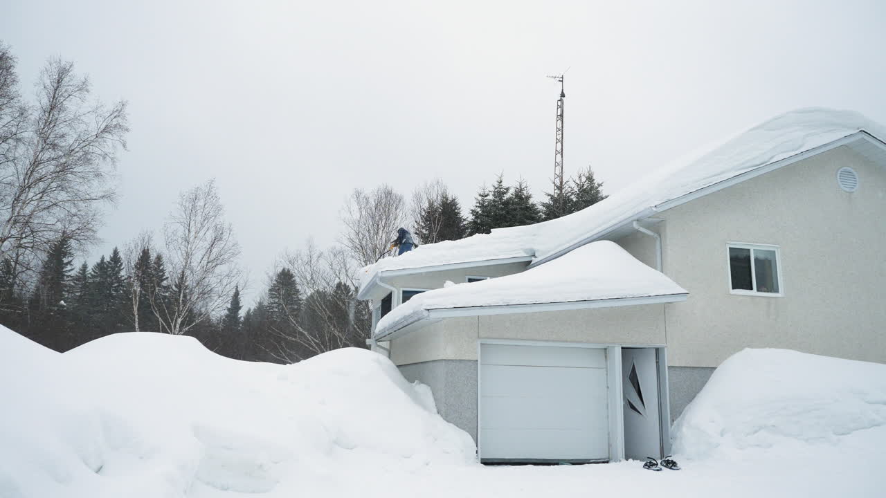 hombre empujando la nieve del techo de la casa después de una tormenta