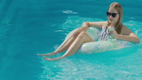 a teenage girl floats in an inflatable circle on the surface of the pool