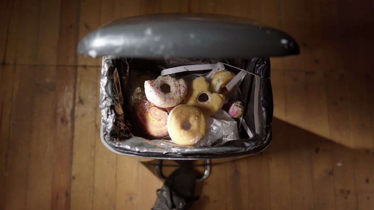 pov de arrojar restos de comida chatarra y dulces en la basura para la resolución de año nuevo