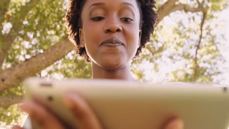 Portrait-of-woman-is-using-a-tablet-in-a-park-