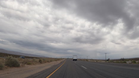 driving along a highway through the mojave desert as the overcast sky threatens rain during a drought year - point of view