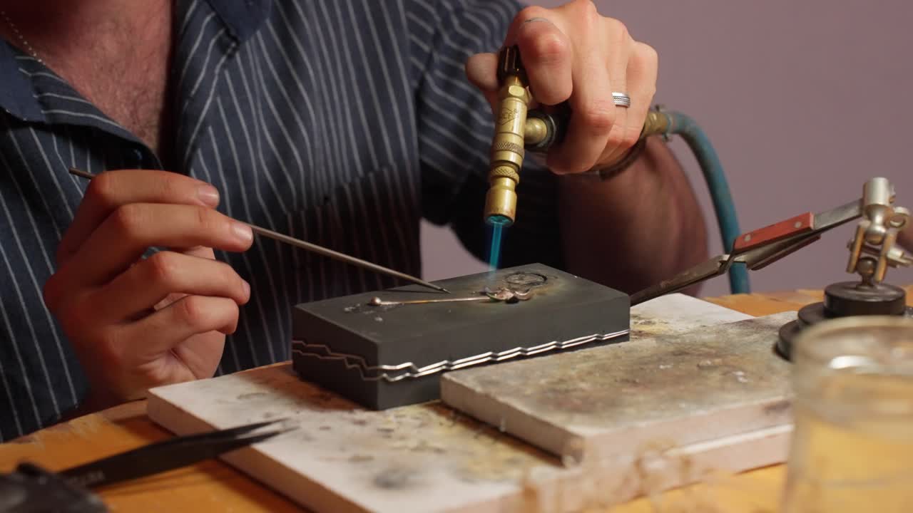 un artesano soldando componentes metálicos en un banco de trabajo en un taller bien iluminado durante la tarde.