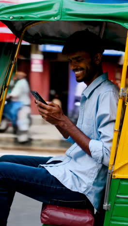 young man using phone in an auto-rickshaw