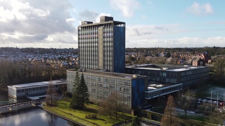 Sede centrale in vetro di Pilkingtons, grattacielo blu per uffici commerciali nel parco, vista aerea ascendente con inclinazione verso il basso.