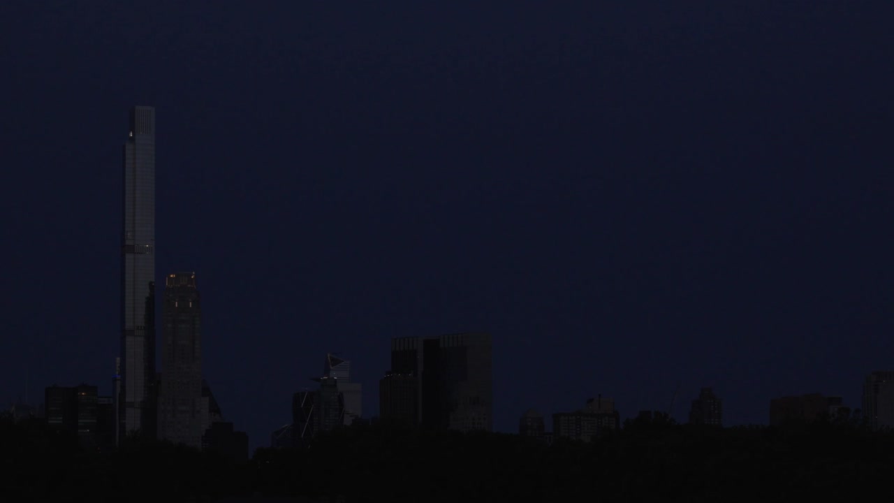 A captivating timelapse shows a strawberry moon setting over billionaire row at dawn, as viewed from Central Park's reservoir in midtown Manhattan