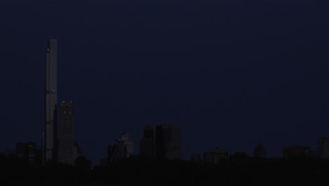 A-captivating-timelapse-shows-a-strawberry-moon-setting-over-billionaire-row-at-dawn,-as-viewed-from-Central-Park's-reservoir-in-midtown-Manhattan