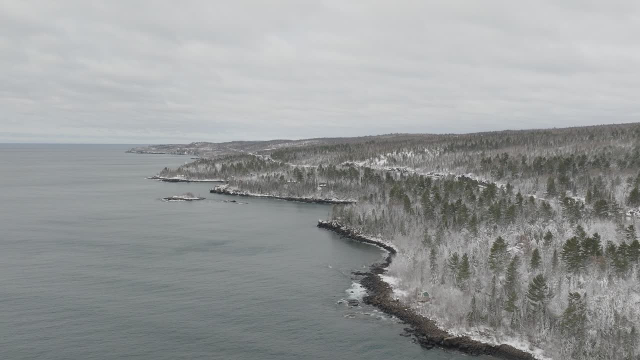 Snow-covered Forest Trees On Shore Of Lake Superior In Winter. Minnesota, USA. wide drone shot