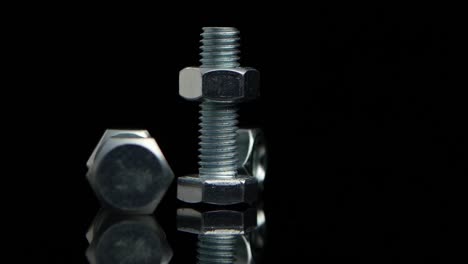 bolts and nuts on a black reflective surface