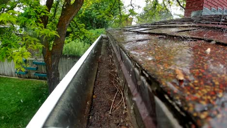 rain water is seen pouring down shingles and a rain gutter in slow motion