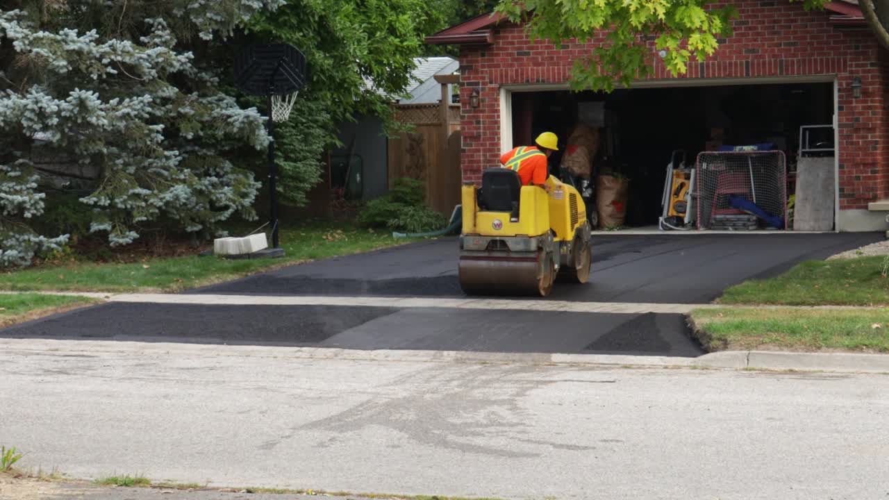Worker Paving a Driveway with an Asphalt Roller