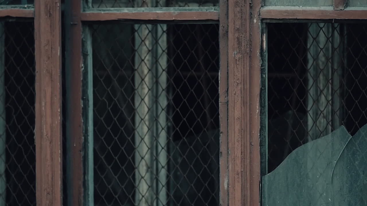 깨진 유리창과 보안 막대기가 있는 버려진 건물 창문