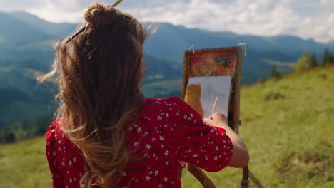 mujer creando imágenes de la naturaleza en las montañas, colina en primer plano. niña dibujando en el prado.