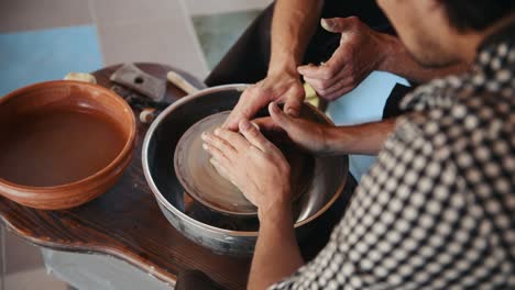 viejo tipo experimentado enseñar al hombre cómo usar la rueda de alfarero para crear producto de arcilla hecho a mano