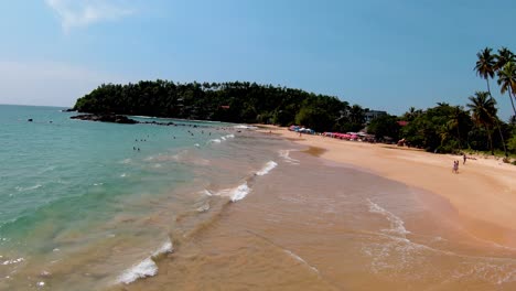 overtake shot of tropical sea and shining golden waves splash on beach, sri lanka