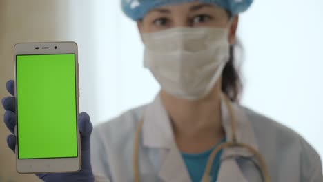 close up de pantalla verde en el teléfono sostenido por el científico. mujer médico sosteniendo el teléfono con pantalla verde hasta la cámara para la composición. mujer profesional médico mostrando teléfono inteligente móvil con pantalla verde.