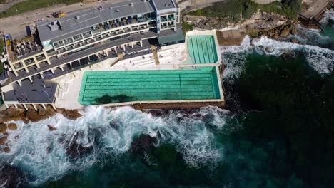 Vista-Aérea-De-La-Piscina-De-Agua-De-Mar-Junto-Al-Restaurante-Icebergs-Cerca-De-La-Playa-De-Bondi,-Sydney,-Nsw,-Australia---Drone-Ascendiendo