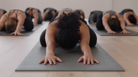 instructor de clase de yoga enseñando a un grupo de mujeres jóvenes y niños posando en una colchoneta de ejercicios disfrutando de un estilo de vida saludable practicando meditación en un gimnasio