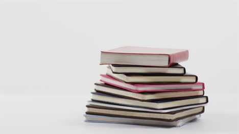 Close-up-of-stack-of-books-on-white-background,-in-slow-motion