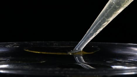 Plastic-Dropper-Pipette-Sucks-Up-Oil-and-Water-Isolated-on-Black,-Closeup