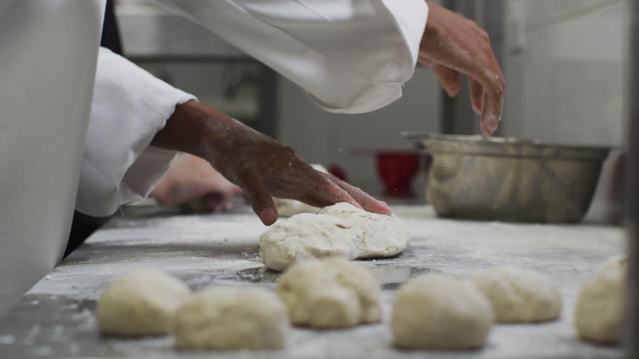 Midsection of mixed race female chef preparing dough adding flour