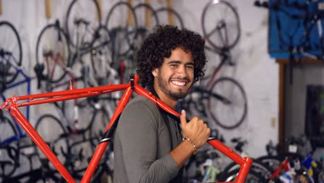 Portrait-of-mechanic-carrying-a-bicycle-in-workshop