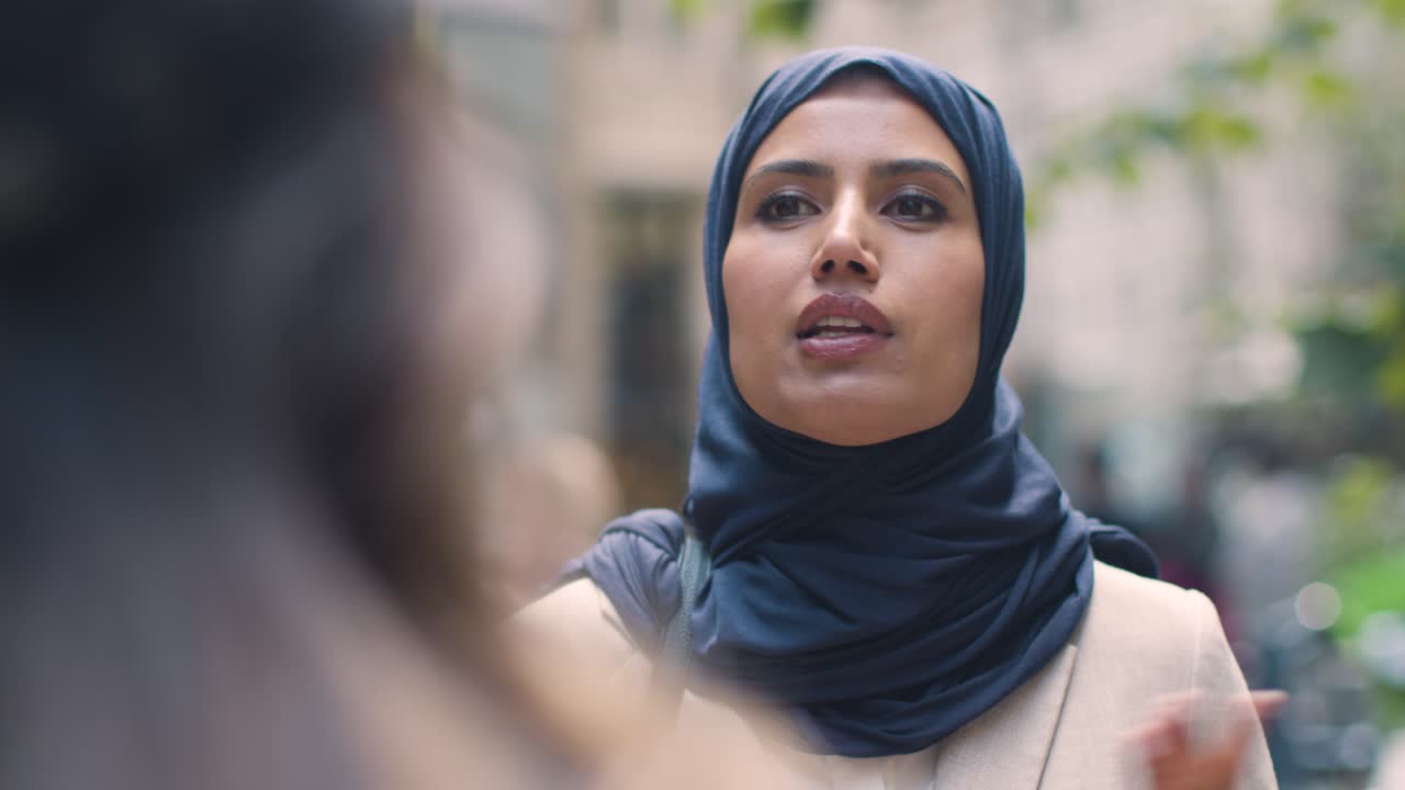 무슬림 사업가 여성 이 동료 와 대화 하고 있는 도시 사무실 앞 에 서 있다