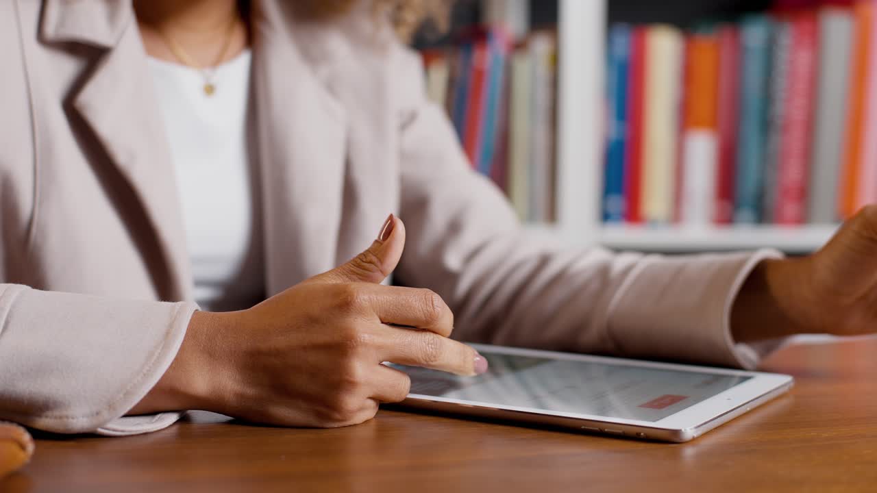 Primo piano di una donna d'affari che legge dati su tablet alla scrivania in ufficio