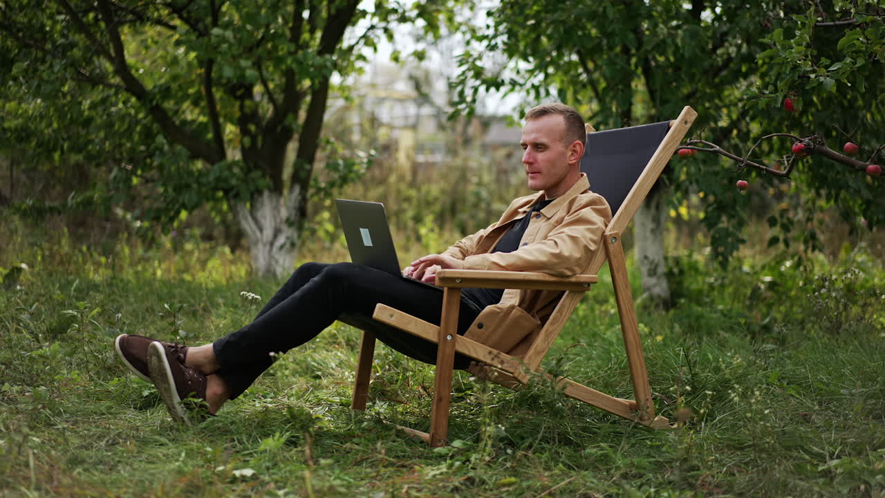 Man working on a laptop in a garden chair