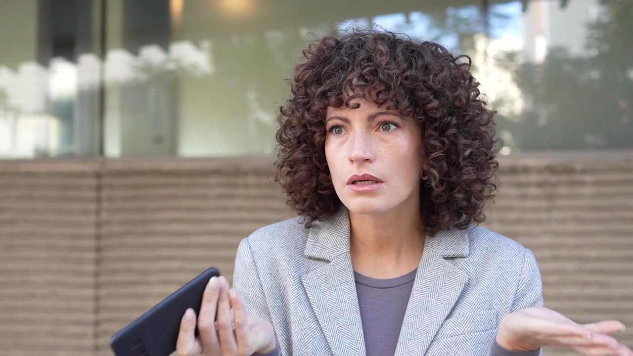 Een vrouw is aan het sms'en op haar smartphone terwijl ze zich in een bruisende stedelijke omgeving bevindt.