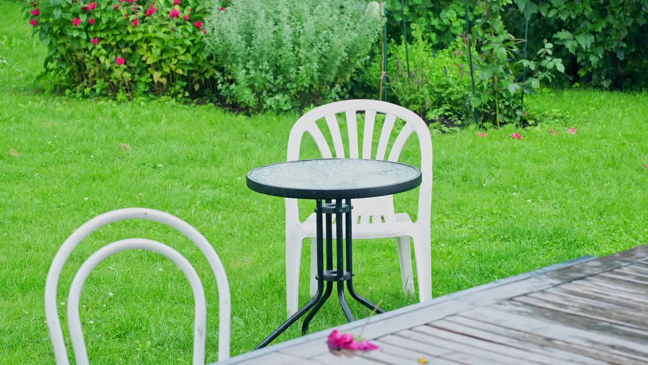 Dešťové kapky padají na zahradní stůl, evokující klidnou a poklidnou venkovní atmosféru.