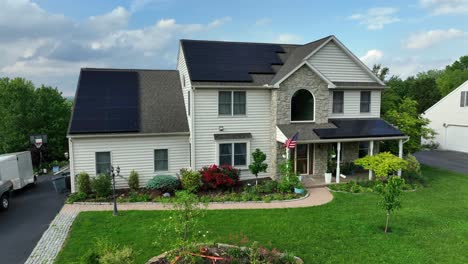 new colonial single family house with patriotic american flag and solar panels on roof. cloudy spring day in may. well-kept garden in luxury district of american town. aerial view.