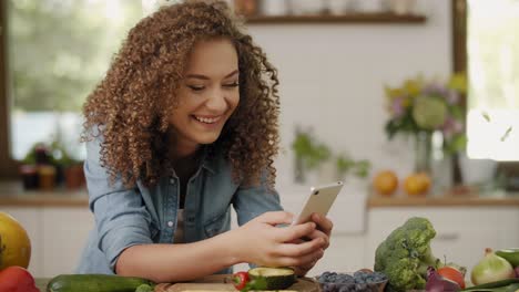 Handheld-view-of-young-woman-with-mobile-phone-in-the-kitchen/Rzeszow/Poland