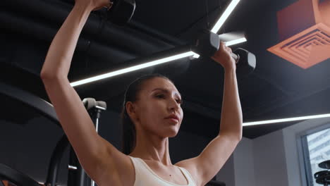 woman doing shoulder press in a gym