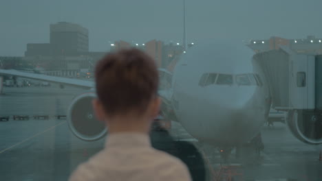 niño mirando el avión a través de la ventana del aeropuerto
