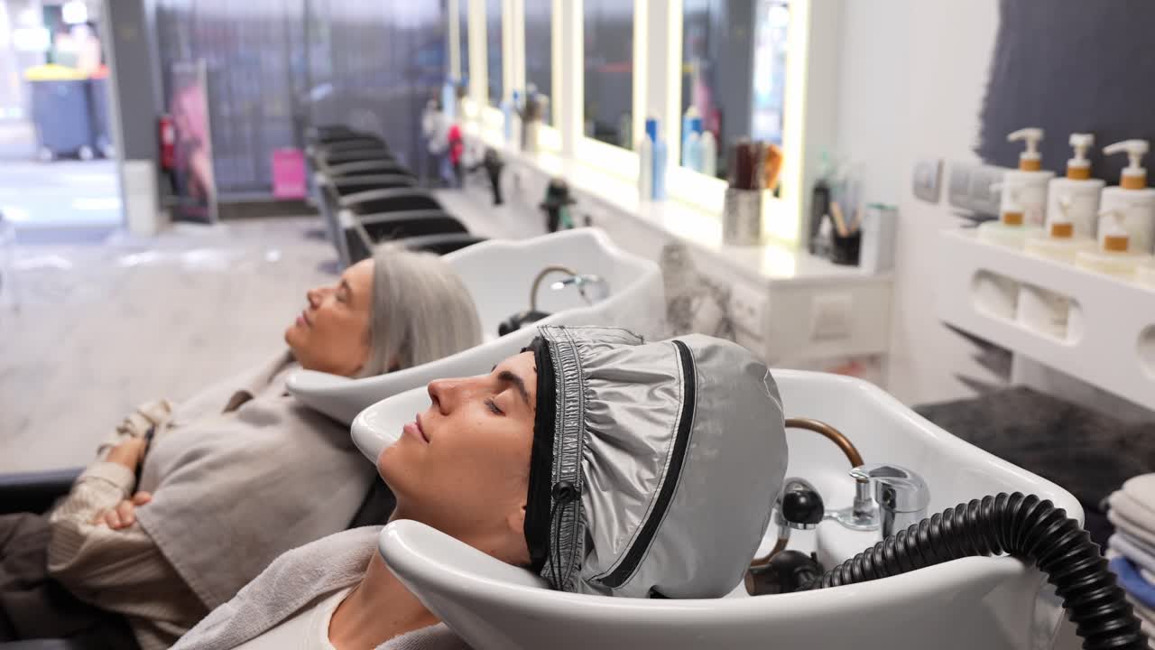 Due donne si rilassano durante un trattamento per capelli in un salone moderno