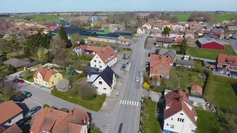 Toma-Aérea-De-Un-Pequeño-Pueblo-Llamado-Löderup-En-El-Sur-De-Suecia-Skåne-Con-Un-Auto-Blanco-Conduciendo