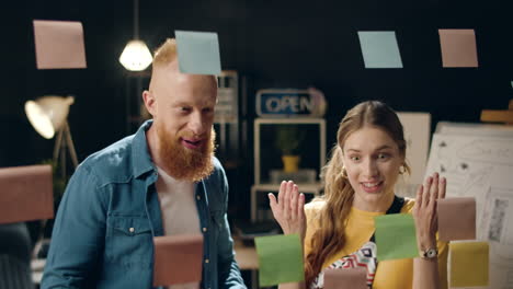 Closeup-satisfied-male-and-female-professionals-giving-high-five-in-night-office