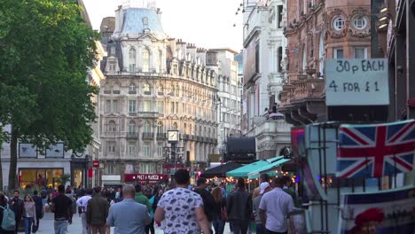 lots of foot traffic and pedestrians move through leicester square london england