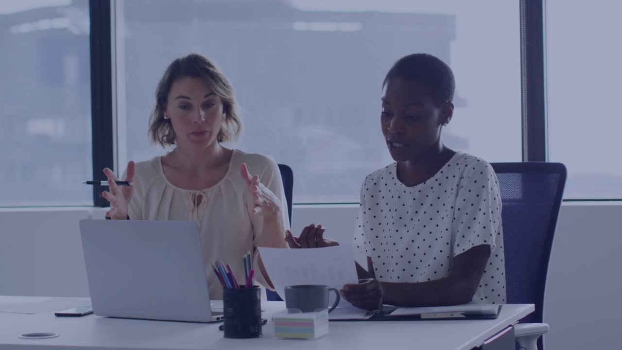 Coworkers gesturing at laptop when social alerts emerging then fading before resuming discussion