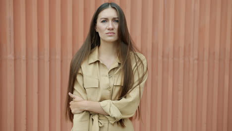 woman in beige jumpsuit against a metal wall