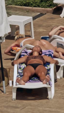 beautiful young women relaxing on the deck chair near the pool