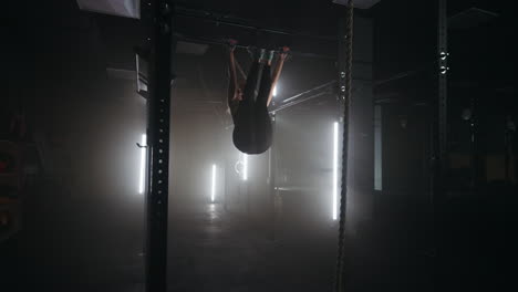 female-athlet-is-doing-exercise-on-crossbar-in-fitness-center-training-alone-in-gymnastic-hall