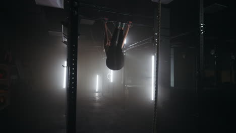 female athlet is doing exercise on crossbar in fitness center training alone in gymnastic hall