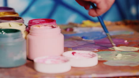 hand-painter artist mixes paint nearby stands a jar of paint