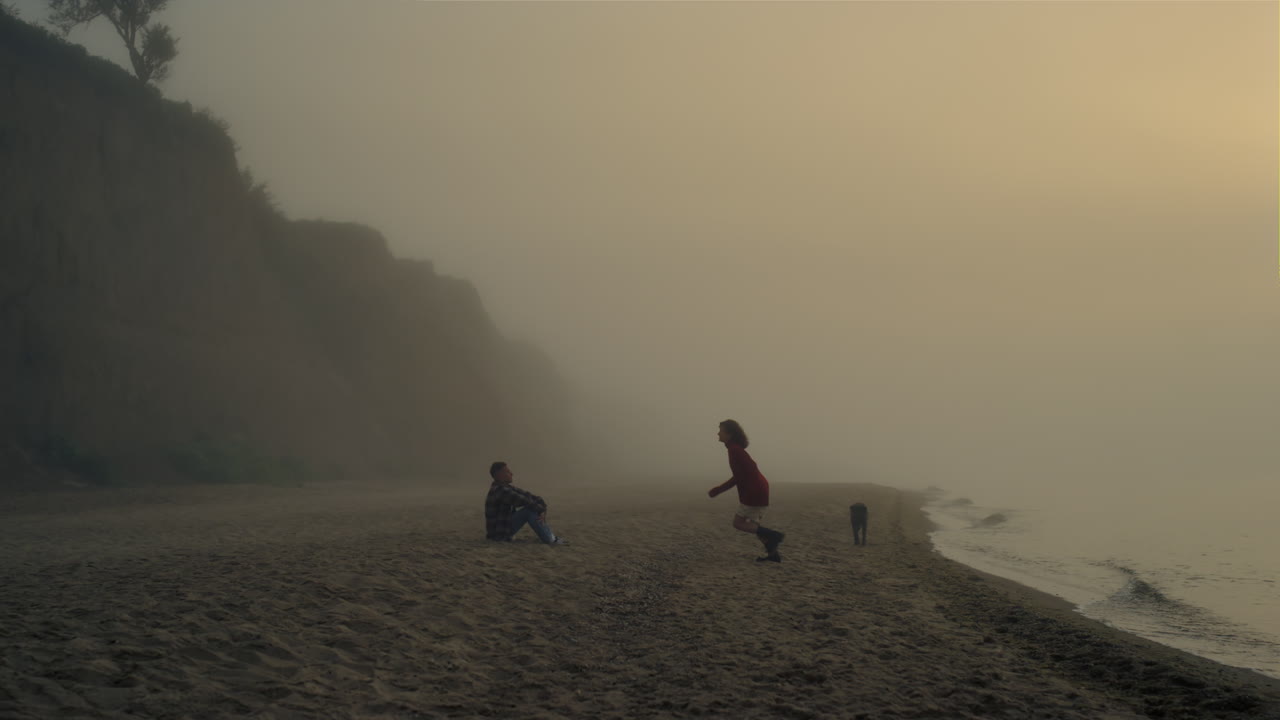 해가 뜨면 해변에서 휴식을 취하는 젊은 부부. 남자친구와 여자친구가 키스하고 있다.