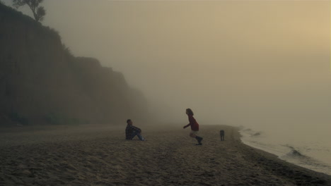 young couple relaxing on beach at sunrise. boyfriend and girlfriend kissing