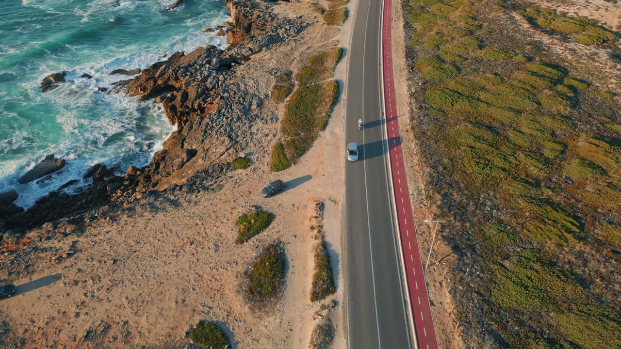 Highway running ocean coast summer day aerial view. Foamy ocean waves crashing
